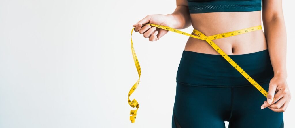 A woman tracking her progress with a measuring tape.