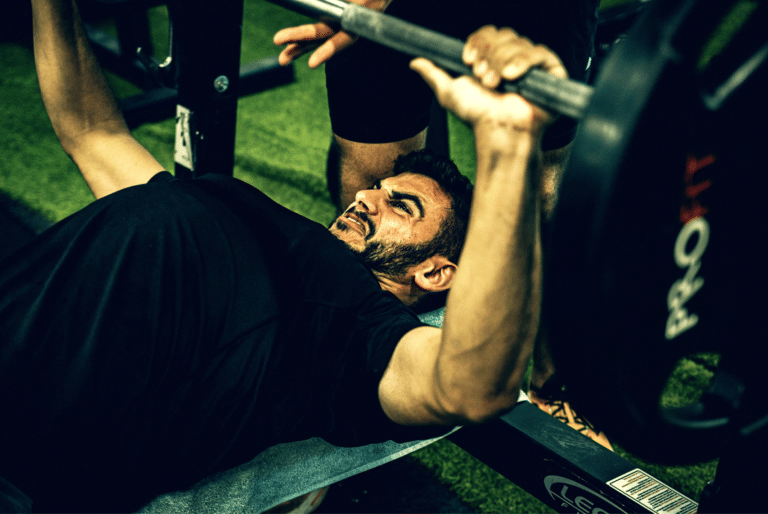 A man struggling to do bench press using the myo rep method.