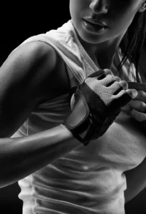 A fitness model holding a towel looking over her left shoulder with a black background